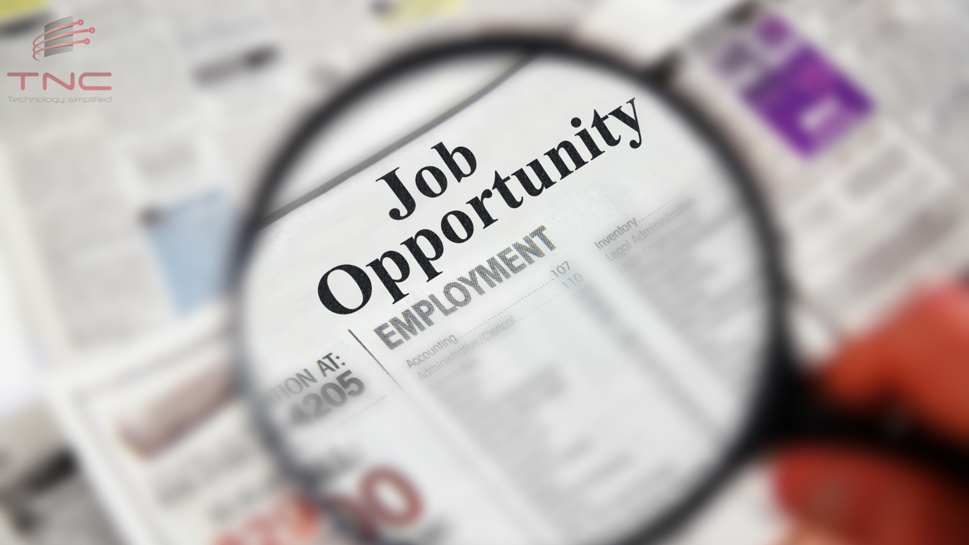 A news paper with "job opportunity" focused on a magnifying glass